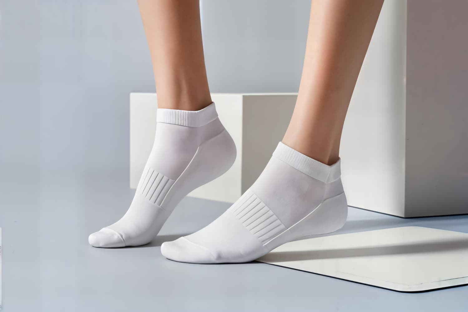 Close-up of white ribbed ankle socks with a ventilated side panel, worn on a model's feet